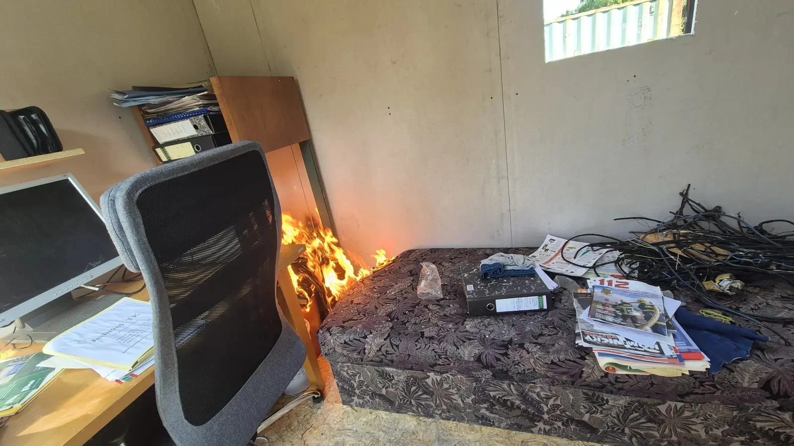 Flames developing between the storage furniture and the bed